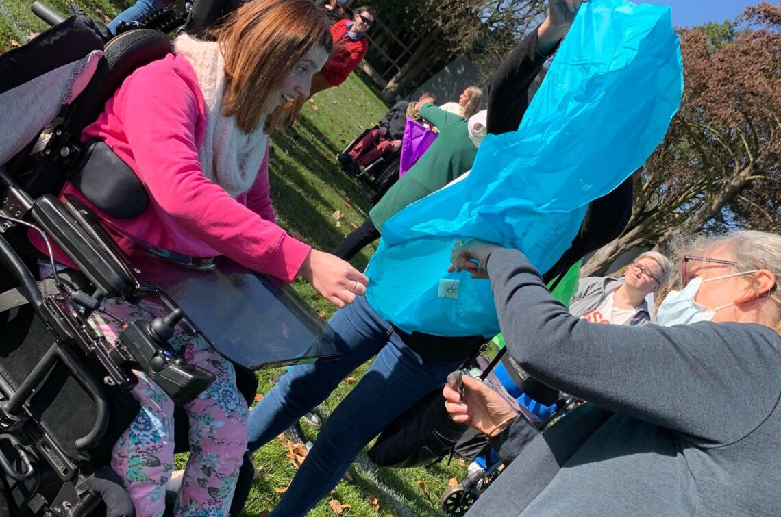 Girl in wheelchair being given small gift while outside